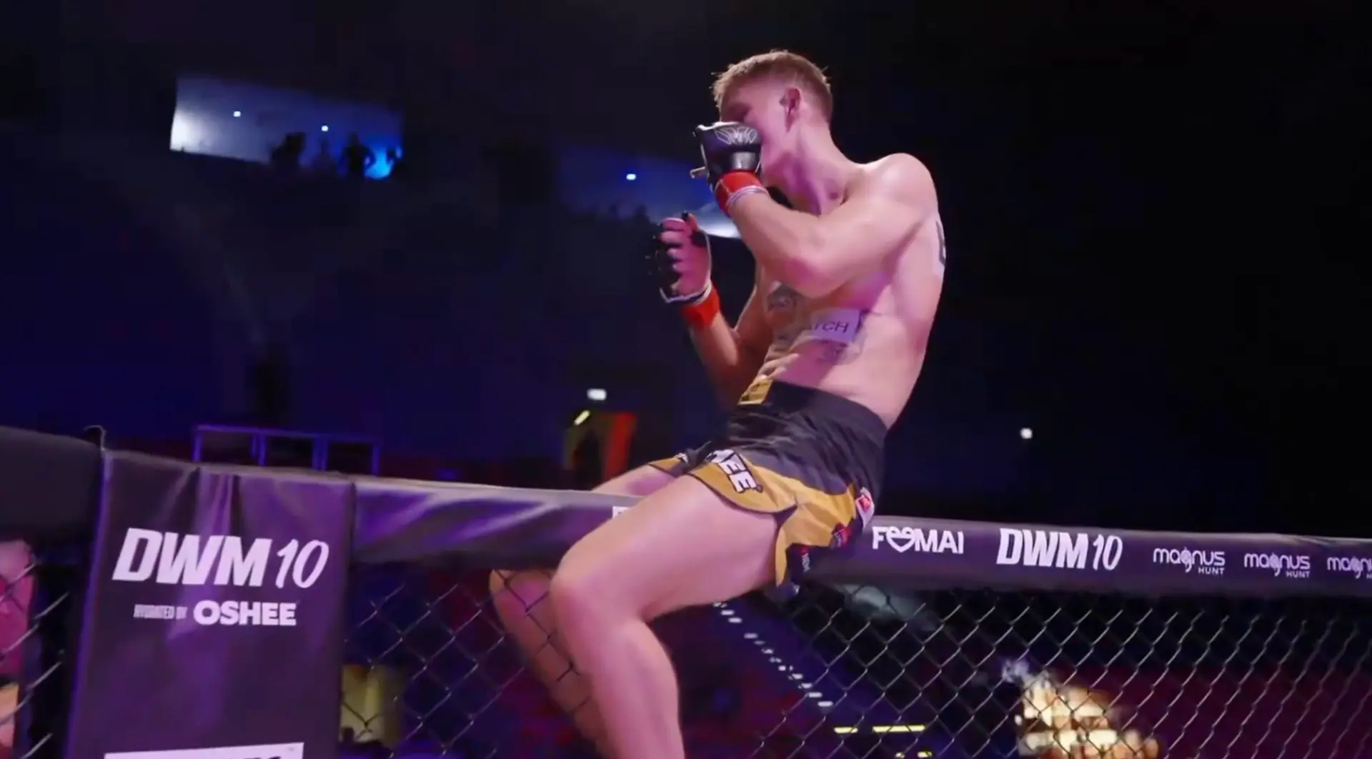 The fighter sitting on top of the cage, smoking, completely unbothered